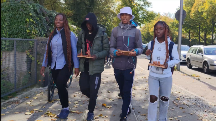 Schüler:innen tragen ihre Tonskulpturen.