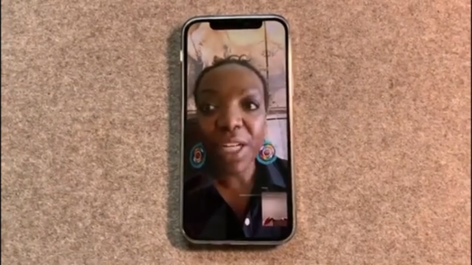 Foto eines Handys, auf dem eine Frau, während eines Videocalls zu sehen ist.