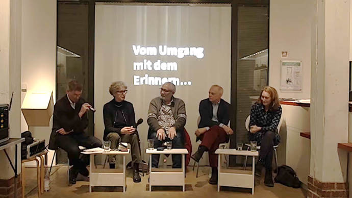 Podium mit 5 Personen, 3 Männer, 2 Frauen sitzen zusammen und sprechen.