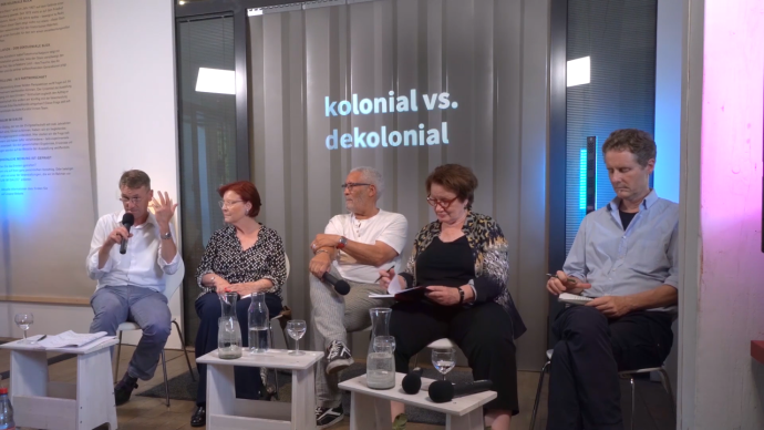 Zwei Frauen und drei Männer sitzen zusammen auf einer Podiumsdiskussion und reden.