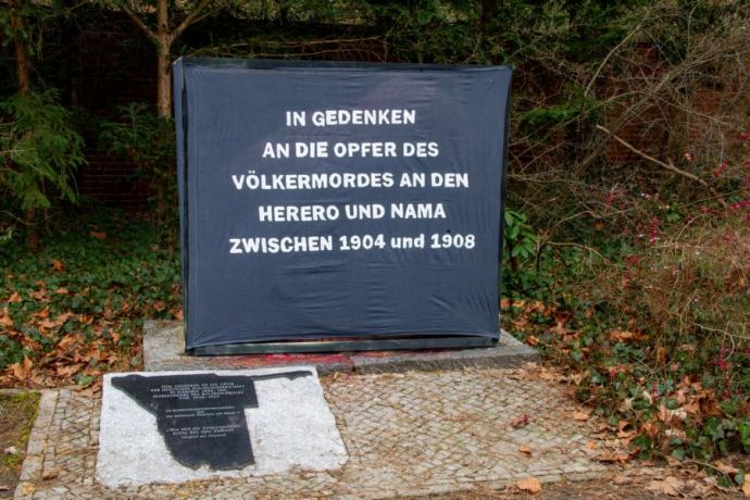 Zu sehen ist ein schwarzer Kasten, mit weißer Schrift: In Gedenken an die Opfer des Völkermordes an den Herero und Name zwischen 1904 und 1908.